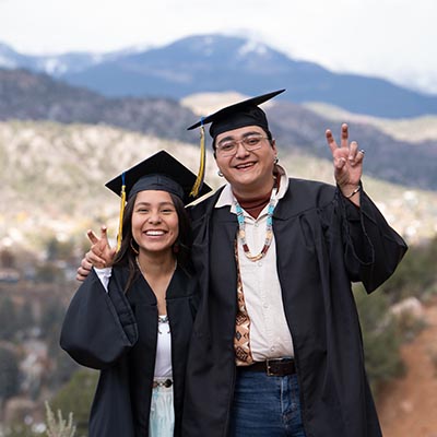 Students pose together in their caps and gowns on the FLC Rim.
