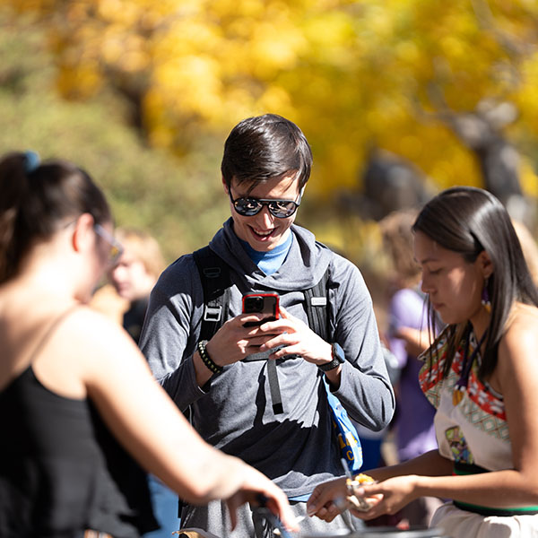 A student smiling and looking at their phone while at an FLC event.