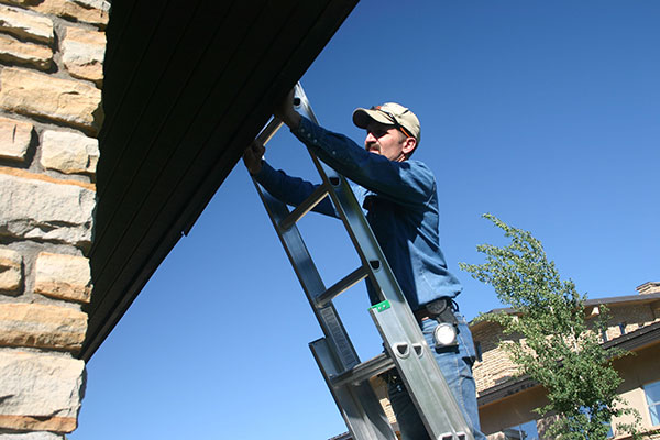 man on ladder looking at roof